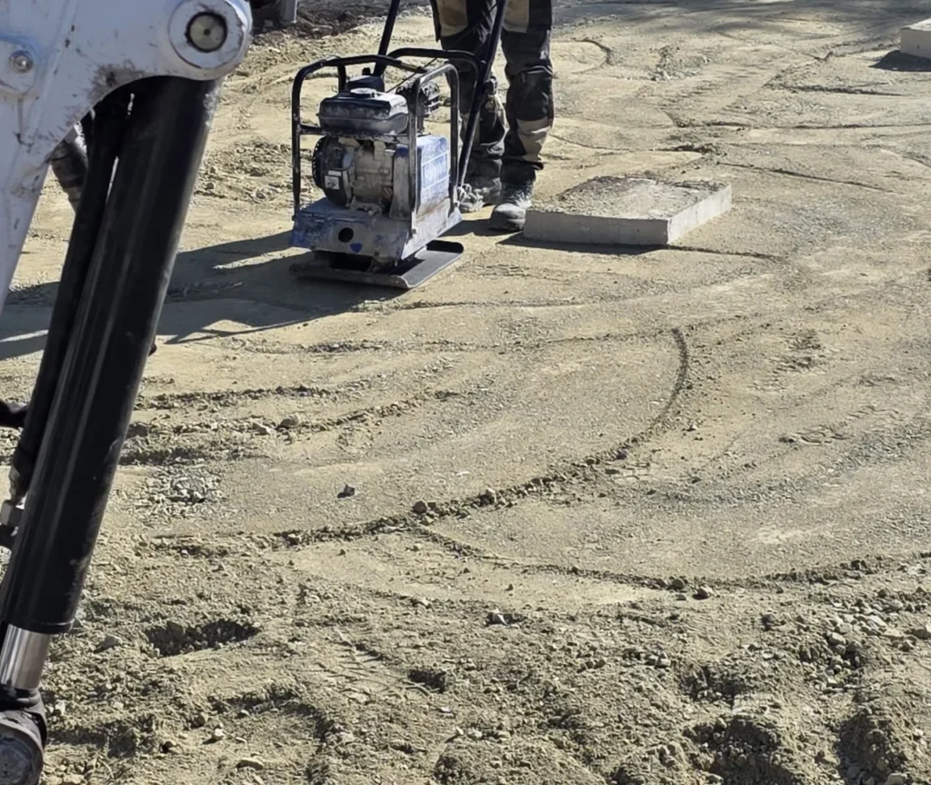 Verdichten von Erde mit Rüttelplatte auf Baustelle